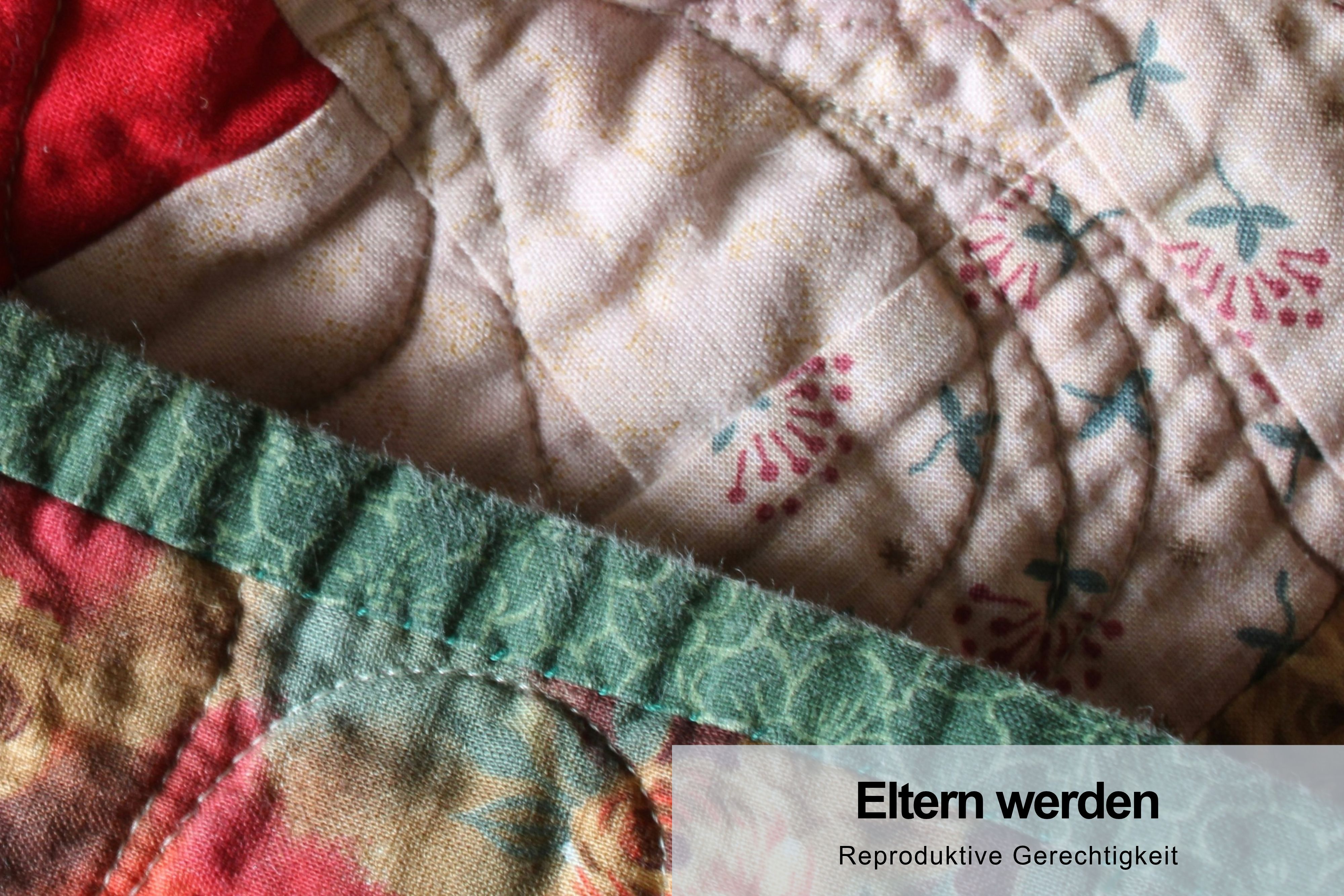 Patchwork-Decke in Pastellfarben mit Stickereien – Symbol für Vielfalt und Fürsorge. Thema: Eltern werden & reproduktive Gerechtigkeit.