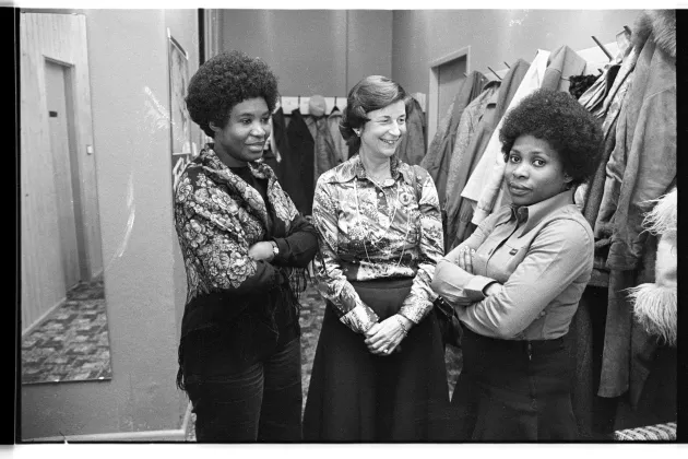 Zwei schwarze Frauen und eine weisse Frau stehen nebeneinander.