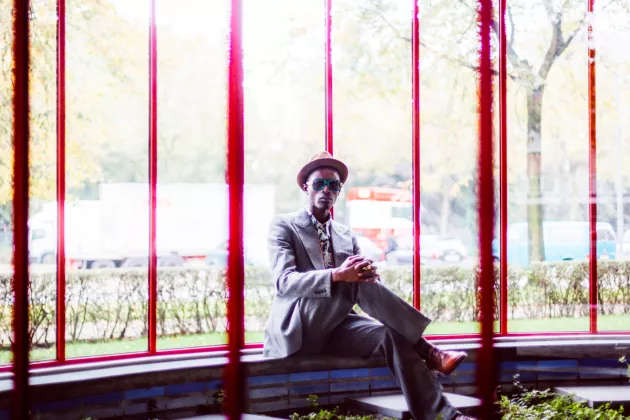 Kongolesischer Sapeur sitz mit überschlagendem Bein.