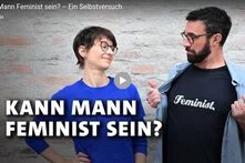 Das Foto zeigt das Titelbild des Kurzfilms "Kann ein Mann Feminist sein?". Rechts zeigt ein männlich gelesener Mensch sein T-Shirt auf dem "Feminist" steht, links neben ihm steht eine weiblich gelesene Person, die das T-shirt skeptisch beäugt. 