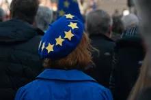A person covered from head to toe in the colours of the European Union stands motionless in the shadow of Nelson’s Column in Trafalgar Square.