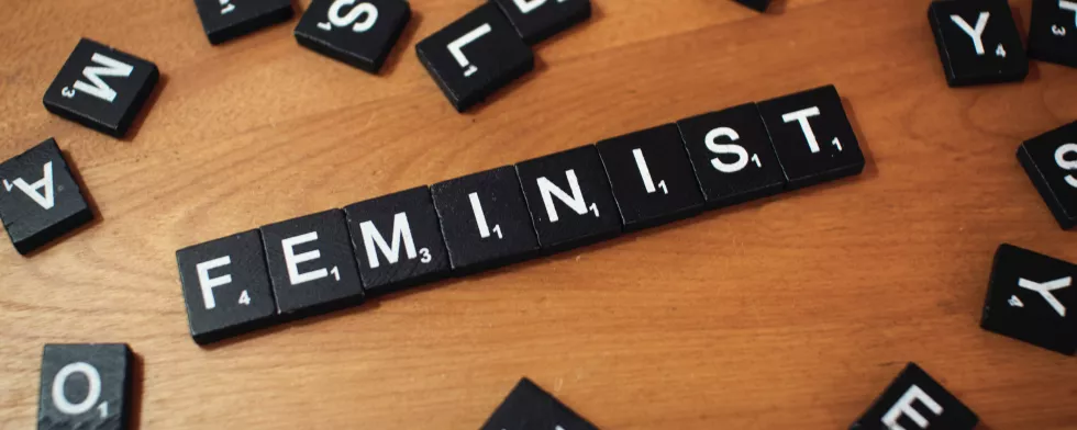 Einzelne Buchstaben liegen zusammengewürfelt auf einer Holzplatte, in der Mitte steht das Wort 