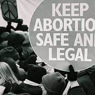 Black and white photo: Demonstration with a hand holding a round sign with the caption 